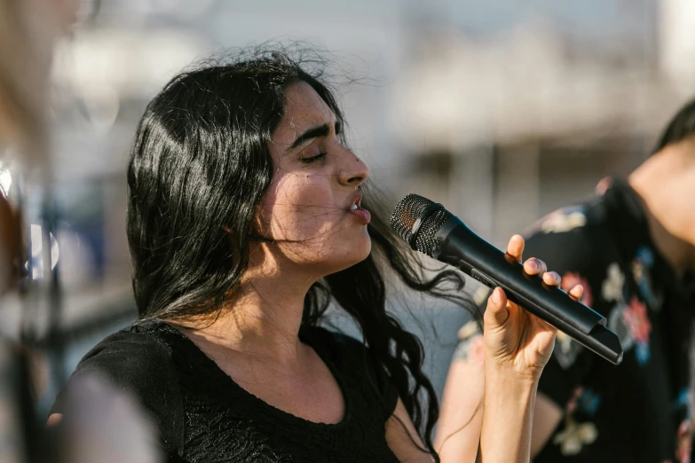 a woman that is holding a microphone in her hand, by Niko Henrichon, pexels contest winner, hurufiyya, female with long black hair, charli bowater and artgeem, harbor, performing