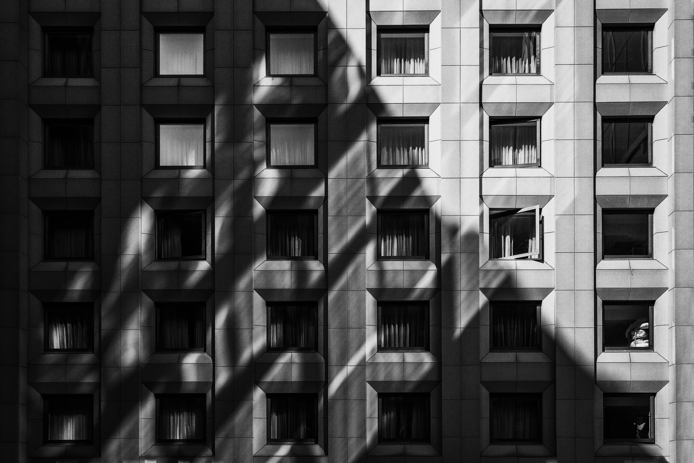 a black and white photo of a tall building, by Tobias Stimmer, unsplash contest winner, beautiful shadows, fire from some windows, grid arrangement, patterned