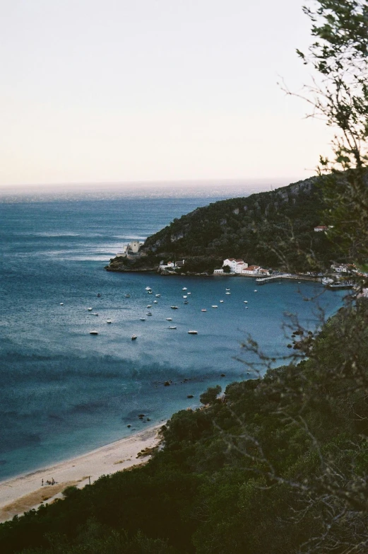 a view of a beach from the top of a hill, boats in the water, lachlan bailey, beautiful low light, very grainy film