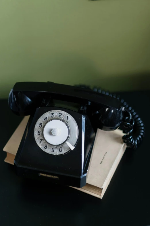 a black telephone sitting on top of a table, an album cover, inspired by Evaline Ness, unsplash, photographed for reuters, 1970's, a handsome, dial