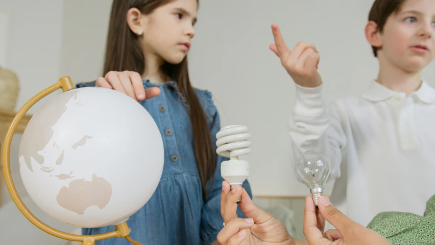 a group of children standing around a globe, a child's drawing, by Adam Marczyński, pexels contest winner, light bulbs, turbines, perfect android girl family, holding an epée