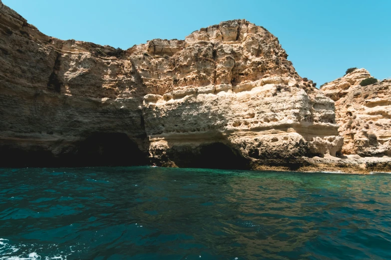 a cave in the middle of a body of water, coastal cliffs, on a boat, lachlan bailey, well preserved