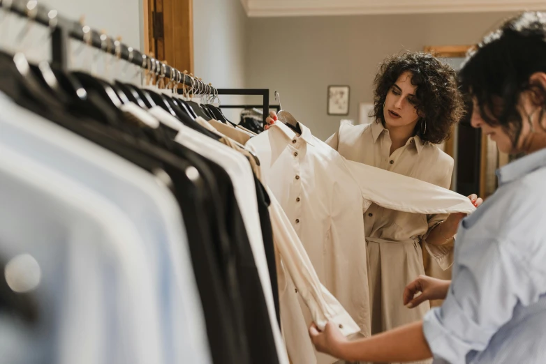 two women looking at clothes on a rack, trending on pexels, wearing a white shirt, thumbnail, looking straight forward, elegantly