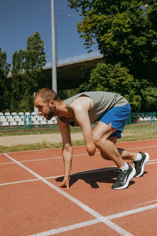 a man is starting to run on a track, by Adam Marczyński, well built, maintenance, backdrop, high-quality photo