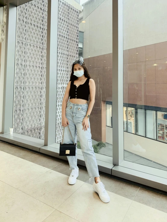 a woman wearing a face mask standing in front of a window, by Robbie Trevino, croptop, ootd, in a mall, full body photo