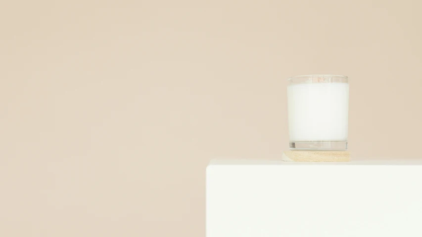 a glass of milk sitting on top of a white box, by Nicolette Macnamara, trending on unsplash, minimalism, on a candle holder, ignant, light wood, white background wall