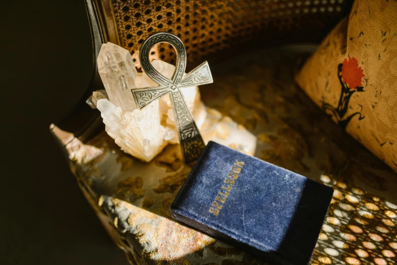 a book sitting on top of a chair next to a cross, amulet, miscellaneous objects, religious imagery