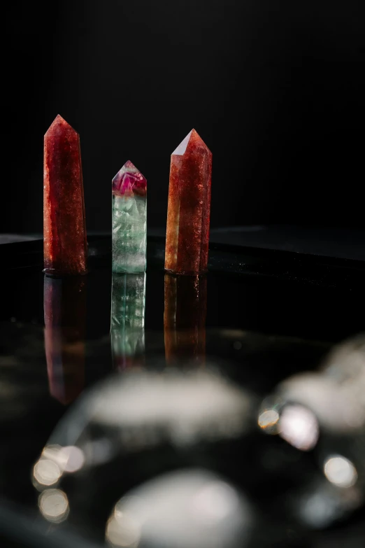 a group of crystals sitting on top of a table, viridian and venetian red, three towers, shot with sony alpha, crystalline masterpiece implants