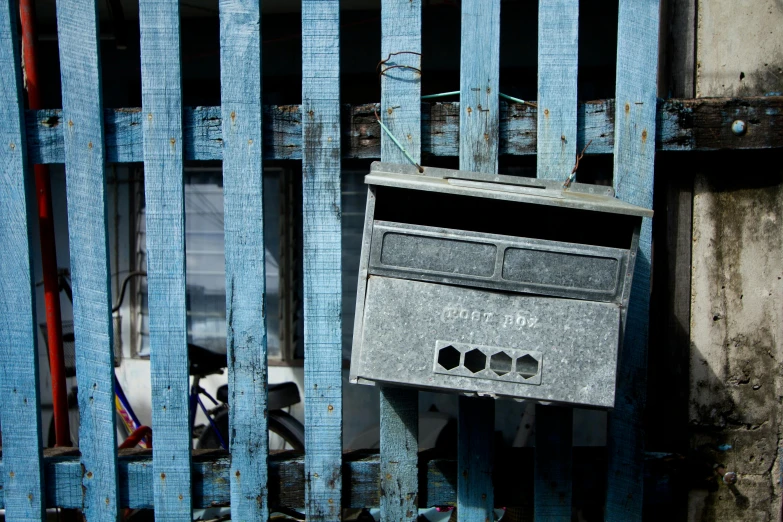 a mailbox sitting on the side of a blue fence, an album cover, unsplash, scrap metal, slum, ignant, old furnitures