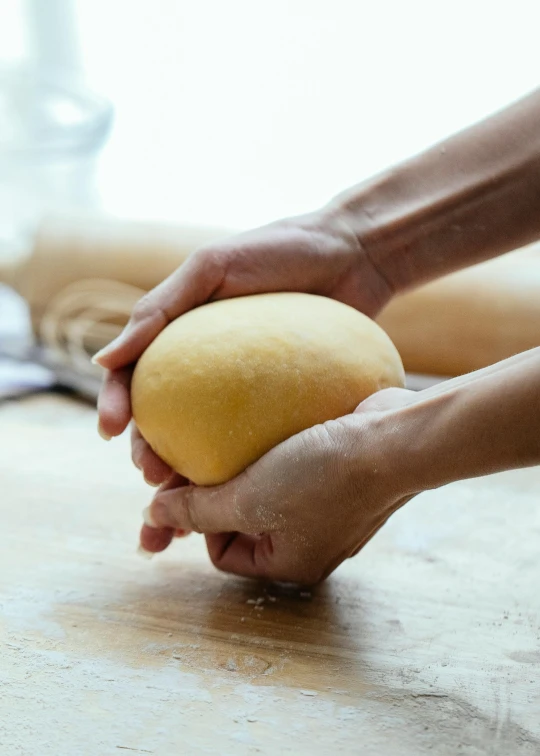 a person holding a ball of dough on a table, square, mango, upper body image, uncompressed