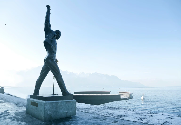 a statue of a man standing next to a body of water, inspired by Wilhelm Freddie, pexels contest winner, modernism, freddie mercury, swiss modernizm, (1 as december, breakfast