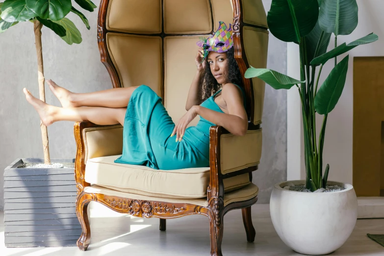 a woman sitting in a chair with a flower crown on her head, inspired by Daphne Allen, pexels contest winner, belly free teal dress, lounge furniture, with brown skin, wearing a party hat