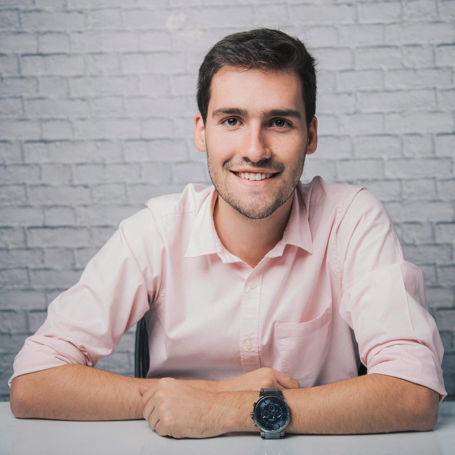 a man sitting at a table in front of a brick wall, a picture, avatar image, diego fernandez, engineer, plain background