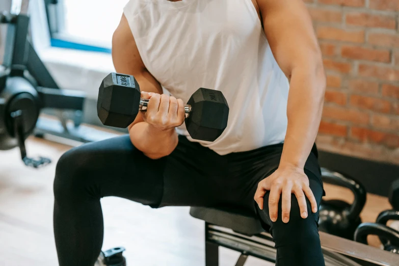 a man sitting on a bench with a pair of dumbbells, by Sam Charles, pexels contest winner, hurufiyya, up to the elbow, hoang lap, lachlan bailey, local gym