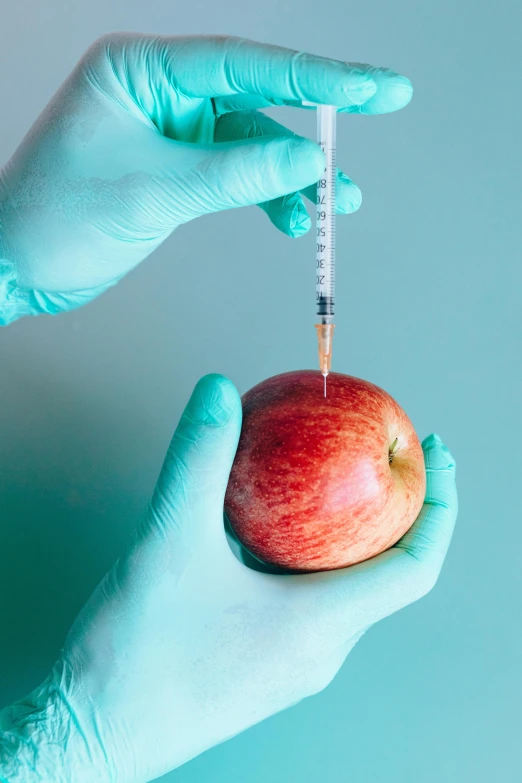 a person in blue gloves holding an apple, holding syringe, made of food, uncrop, diagnostics