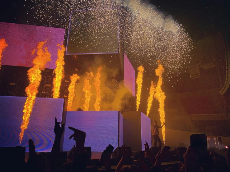 a group of people standing on top of a stage, by Robbie Trevino, shock art, pyrotechnics, post malone, fire from some windows, in an arena pit