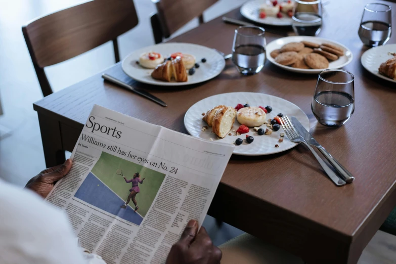 a person sitting at a table reading a newspaper, a still life, by Dietmar Damerau, unsplash, happening, serena williams, breakfast buffet, shot on hasselblad, sports illustrated