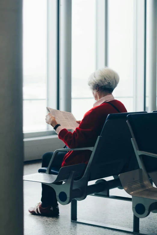 a woman sitting on a bench reading a book, by Will Ellis, pexels contest winner, modernism, airport, dementia, waiting room, thumbnail