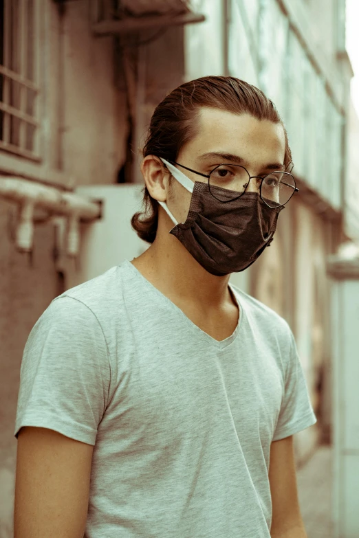 a man wearing a face mask on a city street, an album cover, shutterstock, renaissance, wearing black glasses, profile image, pollution, in an alley