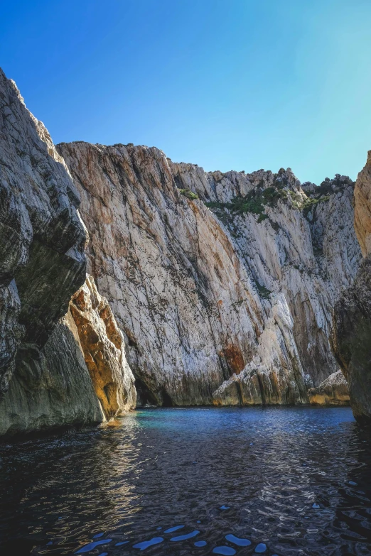 a body of water surrounded by large rocks, by Carlo Carrà, unsplash, les nabis, steep cliffs, croatian coastline, deep colours. ”