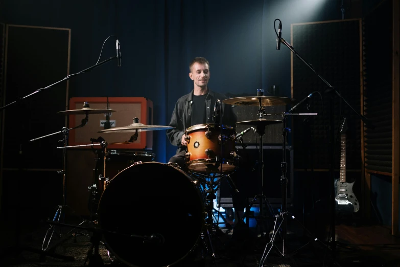 a man that is sitting in front of a drum, sitting in front of a microphone, studio backdrop, liam brazier, anton fadeev 8 k