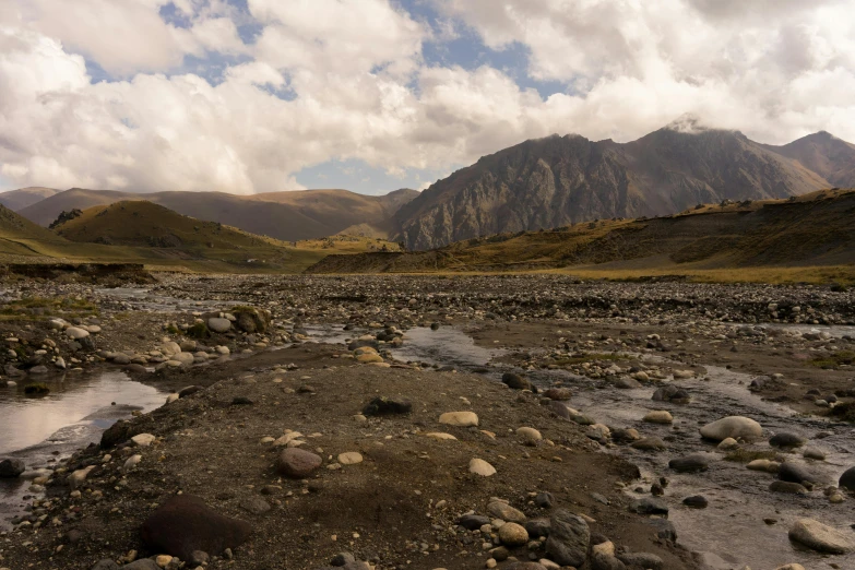 a river running through a rocky valley with mountains in the background, by Muggur, hurufiyya, nature photo