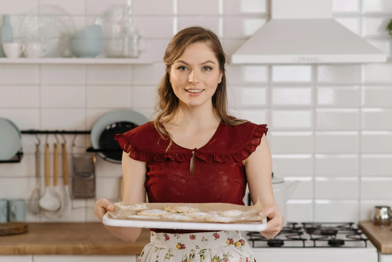 a woman holding a tray of food in a kitchen, a portrait, inspired by Elsa Beskow, pexels contest winner, baking cookies, product introduction photo, thumbnail, portrait of annasophia robb