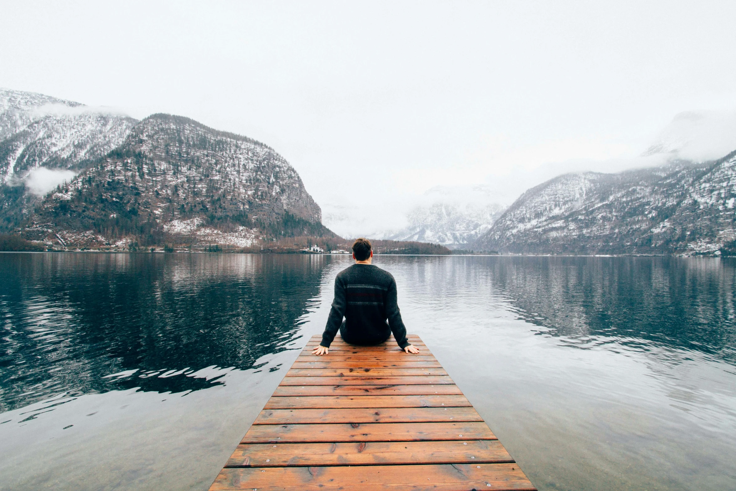 a person sitting on a dock in the middle of a lake, pexels contest winner, winter vibes, gray men, mountains and oceans, on a canva