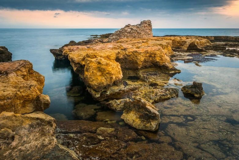 a rock formation in the middle of a body of water, medieval coastal village, byzantine ruins, award - winning photo ”