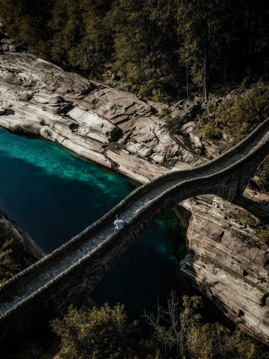 a bridge over a body of water surrounded by trees, by Franz Hegi, pexels contest winner, epic land formations, street of teal stone, slide show, a high angle shot