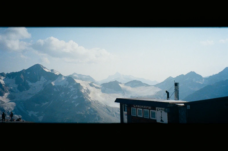 a person standing on top of a snow covered mountain, a matte painting, by Peter Churcher, pexels contest winner, super 8 mm, looking out a window, hasselblad photo, the alps are in the background