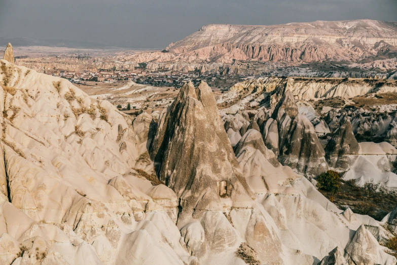 a person standing on top of a rock formation, unsplash contest winner, art nouveau, turkey, beige, view of villages, asymmetrical spires