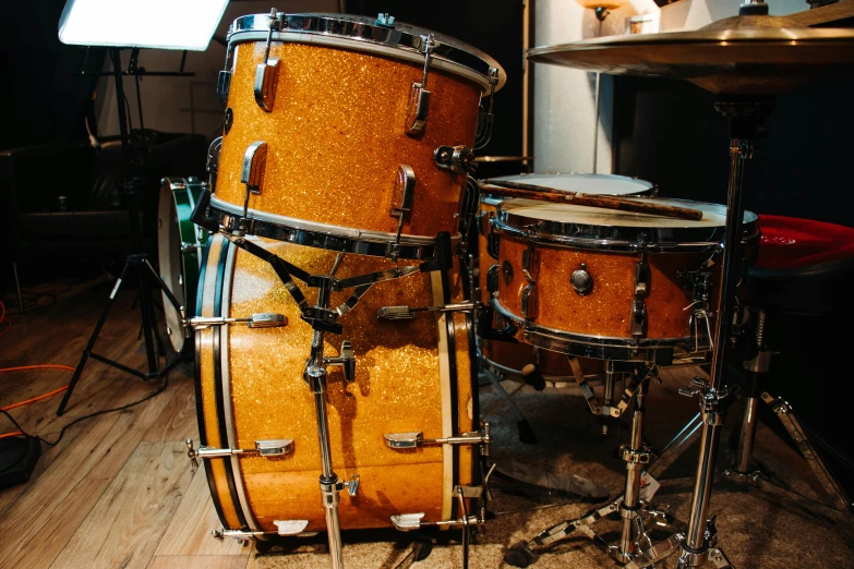 a couple of drums sitting on top of a wooden floor, gold suit, restomod, thumbnail, fluffy orange skin