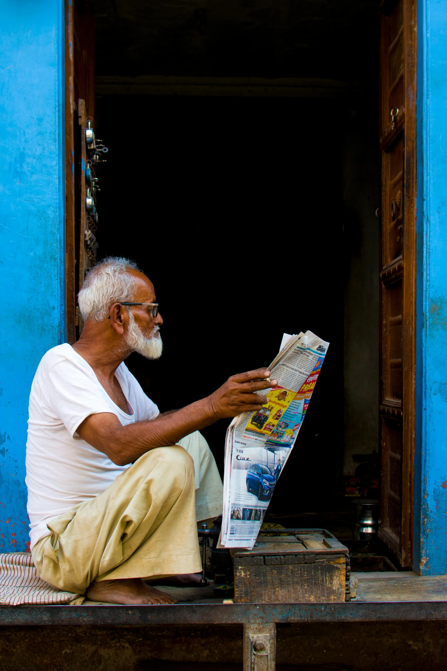 a man sitting on a bench reading a newspaper, a picture, inspired by Steve McCurry, pexels contest winner, dada, manmohan singh blue turban, in an alley, oldman with mustach, sri lanka