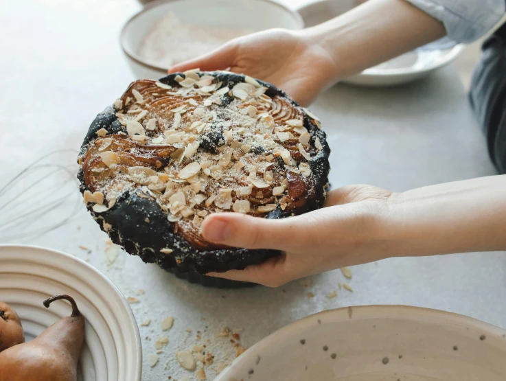 a person holding a cake on top of a table, by Helen Stevenson, unsplash, process art, rusticated stone base, black, handmade pottery, navy