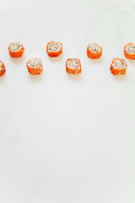 a number of pieces of sushi on a white surface, inspired by Tōshi Yoshida, unsplash, mingei, sugar sprinkled, 3 / 4 wide shot, white and orange, all marble