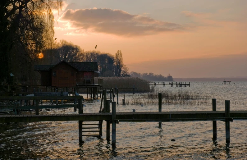 a dock in the middle of a body of water, by Jan Tengnagel, pexels contest winner, romanticism, late afternoon, wooden houses, lake in the background, lower saxony