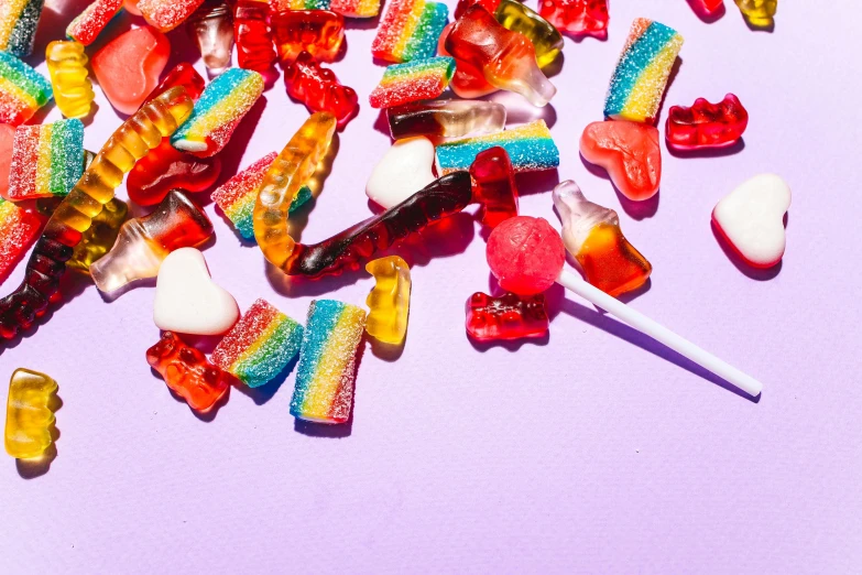 a pile of candy sitting on top of a table, by Julia Pishtar, trending on pexels, rainbow bg, joints, long trunk holding a wand, jelly - like texture