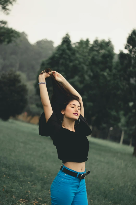 a woman standing on top of a lush green field, wearing a cropped tops, satisfied pose, avatar image, trending photo