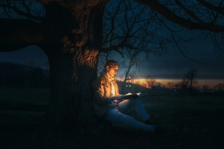 a man sitting under a tree using a tablet computer, a portrait, by Eglon van der Neer, pexels contest winner, magical realism, twilight lighting, trying to read, phot