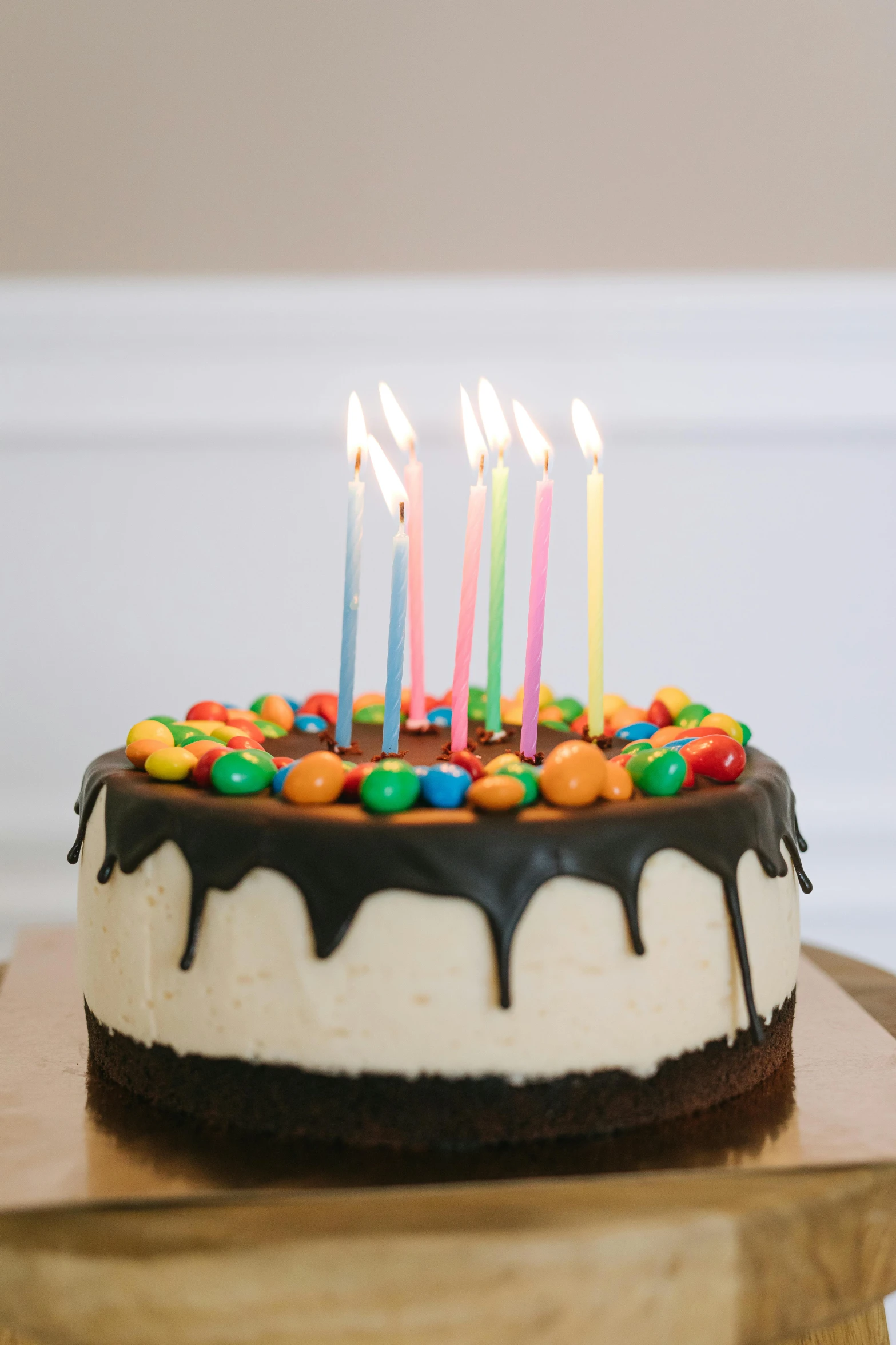 a birthday cake sitting on top of a wooden table, dripping candles, black main color, front facing, full product shot