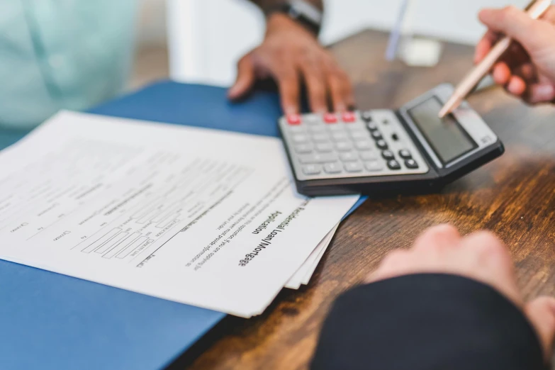 a couple of people sitting at a table with a calculator, by Matt Cavotta, pexels contest winner, highly detailed rounded forms, papers on table, 15081959 21121991 01012000 4k, zoomed in