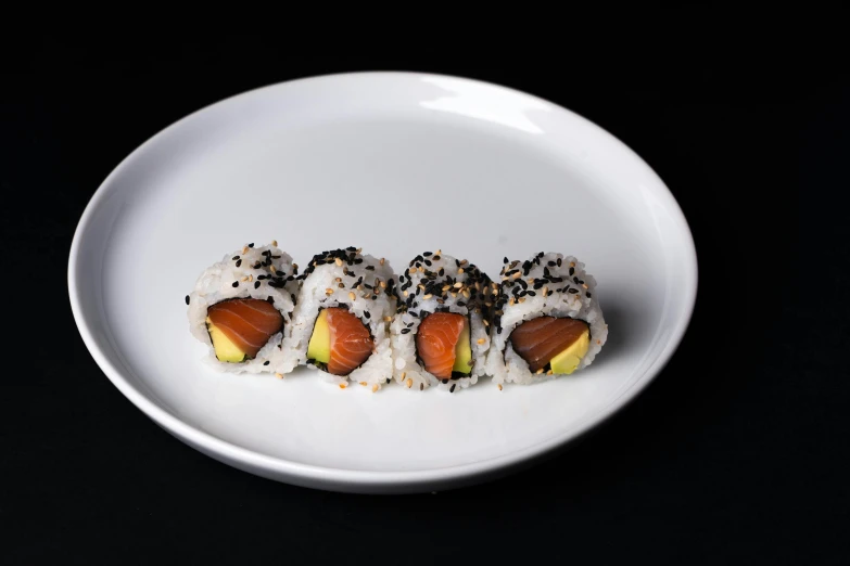 a white plate topped with sushi on top of a black table