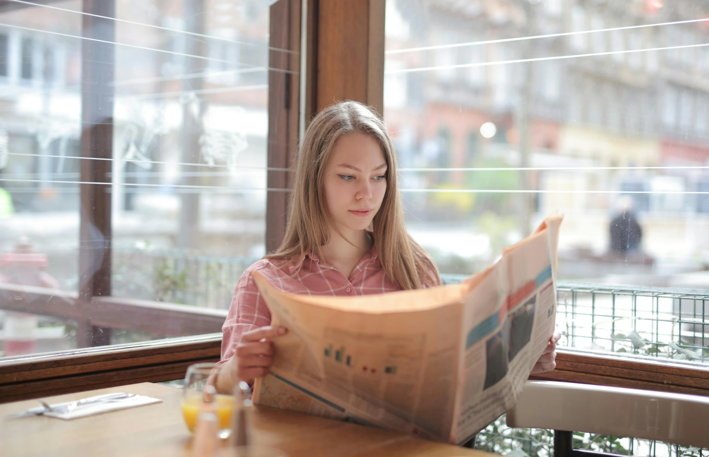 a woman sitting at a table reading a newspaper, by Adam Marczyński, pexels contest winner, handsome girl, gif, breakfast, low quality photo