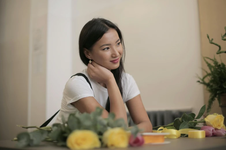 a woman sitting at a table with a bunch of flowers, inspired by Zhang Shuqi, pexels contest winner, looking to the side, young cute wan asian face, on a white table, casual