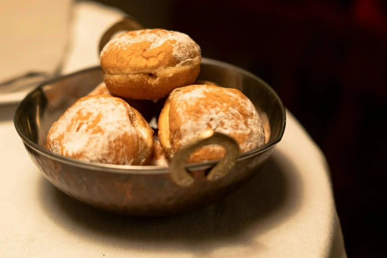 a bowl filled with doughnuts sitting on top of a table, bread, silver, thumbnail, bogna gawrońska