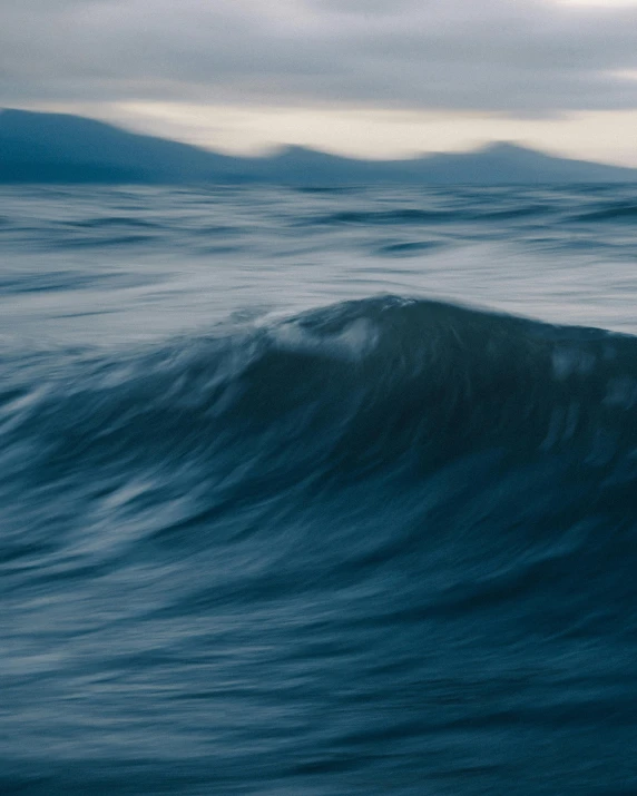 a man riding a wave on top of a surfboard, by Adam Marczyński, unsplash contest winner, surrealism, in thick layers of rhythms, shades of blue and grey, moody evening light, the photo was taken from a boat