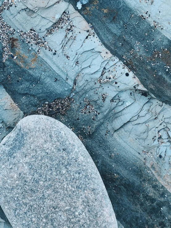 a white toilet sitting on top of a stone floor, an album cover, by Matija Jama, trending on unsplash, concrete art, blue glacier, ((rocks)), intricate wrinkles, blue and grey color scheme