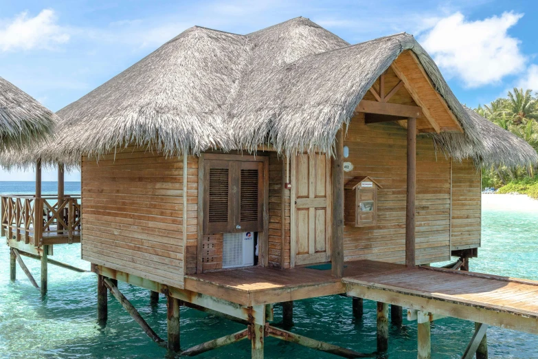 a couple of huts sitting on top of a body of water, pexels contest winner, hurufiyya, luxurious wooden cottage, profile image, bahamas, single floor