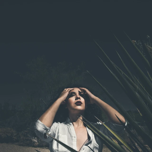 a woman standing in front of a cactus plant, a portrait, inspired by Elsa Bleda, unsplash, grim fashion model looking up, in a dark field, lying down, looking confused